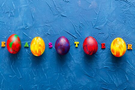 Multi-colored wooden letters making up the words happy easter and decorative colourful eggs on a...