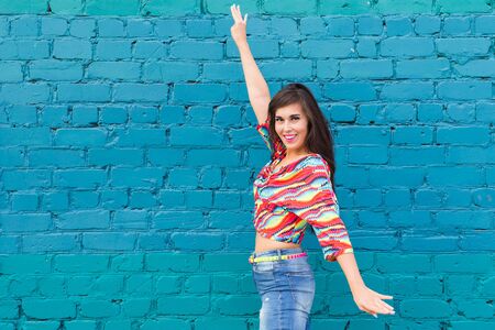Street shaabi dance and urban dancer concept - Cheerful belly dancer dancing with arabic music on the street, blue brick wall background with copy spaceの写真素材