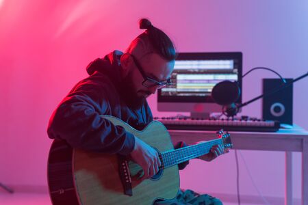 Create music and a recording studio concept - Bearded man guitarist recording electric guitar track...