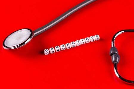Pandemic and virus concept - Coronavirus text and phonendoscope on red background. Novel coronavirus...