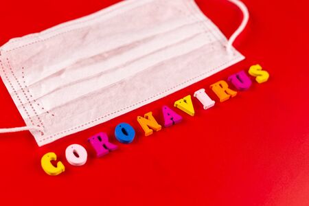 Coronavirus word made of colourful letters on red background . The inscription on medical protective mask coronavirus.の写真素材