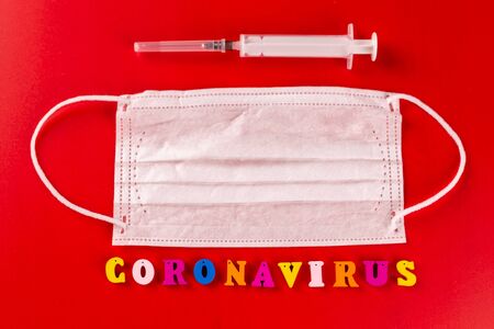 Coronavirus word made of colourful letters on red background . The inscription on medical protective mask coronavirus.の写真素材