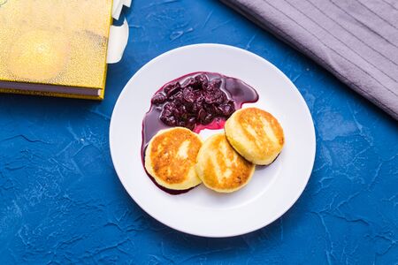 Cottage cheese pancakes with cherry jam, close up, top view.