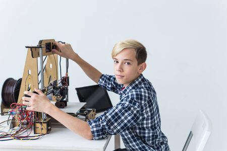 Education, children, technology concept - teen boy is printing on 3d printer.