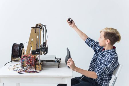 Education, children, technology concept - teen boy is printing on 3d printer.