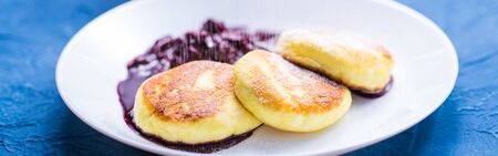 Breakfast and delicious concept - Pancakes from cottage cheese with jam, blue background. Sprinkle...