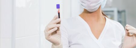 Covid-19, pandemic and viruses concept - hand holding blood in tests tubes close up, white...