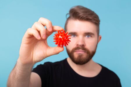 Covid-19, Vaccine development and medicine concept - Man in flu mask and protective gloves holding a model of coronavirus.の写真素材