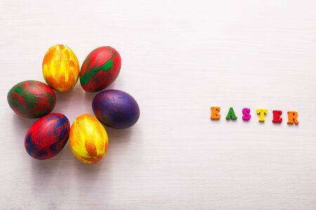 Multi-colored wooden letters making up the words happy easter and decorative colourful eggs on a...