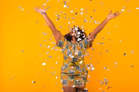 Celebrating happiness, young woman dancing with big smile throwing confettiの写真素材