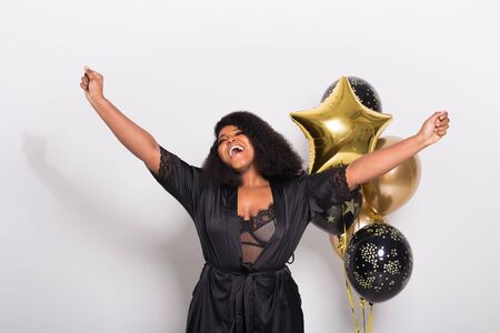 Holidays, birthday party and fun concept - Portrait of smiling young African-American young woman looking stylish on white background holding balloons.の写真素材