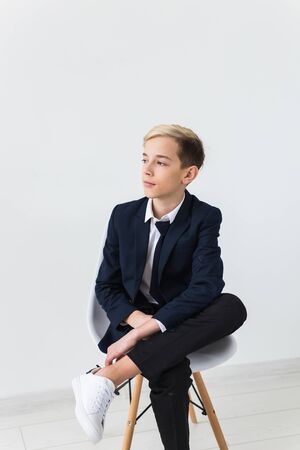 Portrait of stylish school boy teenager in white shirt and jacket against white background.の写真素材