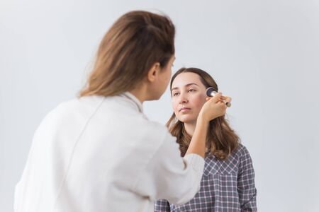 Beauty and cosmetics concept - Makeup artist doing professional make up of young woman