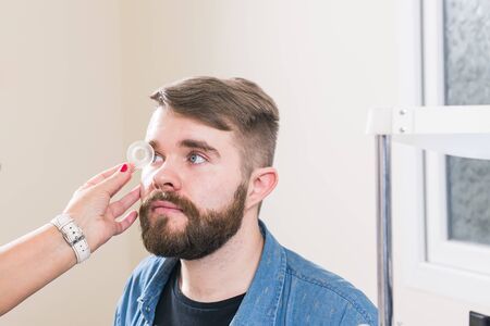 Medicine, health, ophthalmology concept - Ophthalmologist examines patients eyes.の写真素材