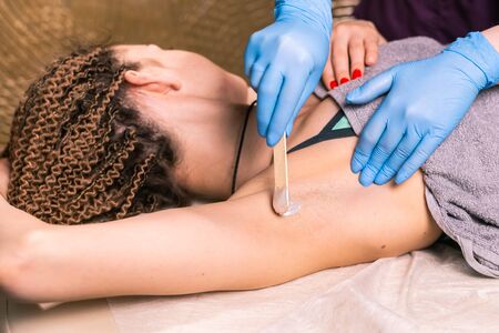 Waxing woman armpit. Salon wax beautician epilation procedure. Waxing female body for hair removal by therapist close up. Smooth underarm concept.の写真素材