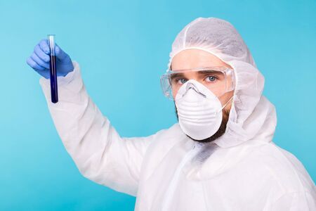 Covid-19, Vaccine development, pandemic, outbreak and coronavirus concept - Man scientist dressed personal protective equipment holding a test tube and does a chemical experiment.の写真素材