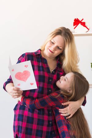 Mothers Day and family holidays - Mother reading greeting card from her daughter.の写真素材