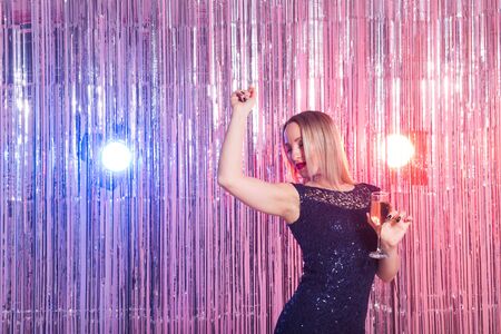 Party, drinks, holidays and celebration concept - smiling woman in evening dress with glass of sparkling wine over shiny background.の写真素材