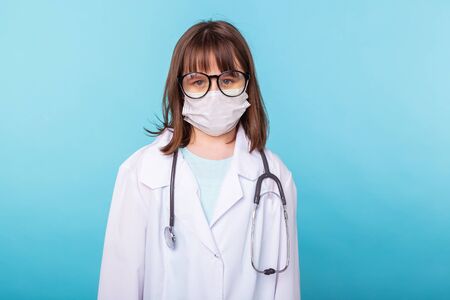 Virus, pandemic, quarantine and outbreak concept - child dressed as a doctor standing over blue background.の写真素材