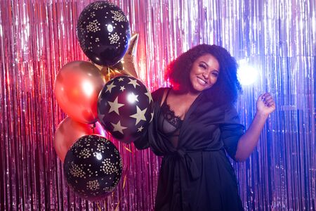 Young black woman looks happy while spend time in night club. Birthday party and nightlife concept.の写真素材
