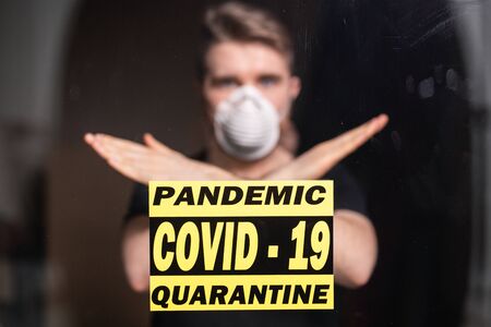 Man in respiratory mask showing stop gesture. Guy show gesture no. Stop coronavirus or covid-19 and the pandemic. Stay home. Quarantine concept.の写真素材