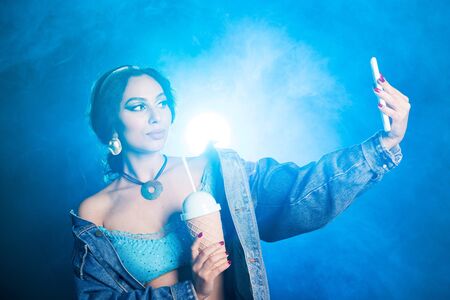 Magic, cosplay and fairy tale concept - Portrait of a young woman in the image of an Eastern fairy Princess takes selfie on blue background.の写真素材