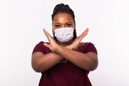 Doctor crossed hands on chest on white background. He is wearing medical mask. No or stop gesture. Coronavirus, covid-19 and pandemic concept.の写真素材