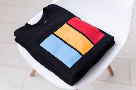 Sweatshirts and hoodies lie on a chair in the store. Street fashion, unisex and youth wearsの写真素材
