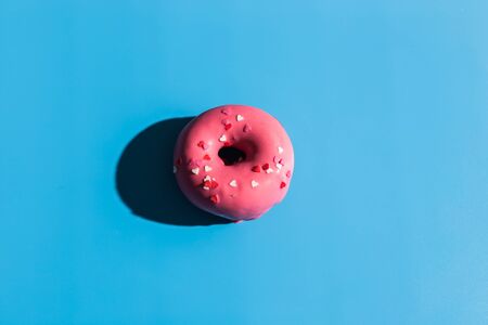 Colourful round donuts at bright blue background. Sweet donuts. Trendy sunlight Summer pattern Minimal summer conceptの写真素材