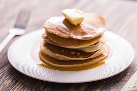 Golden pancakes with butter and warm maple syrup