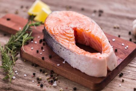 Raw salmon steak on wooden board. Healthy food, diet and mediterranean cuisine.の写真素材