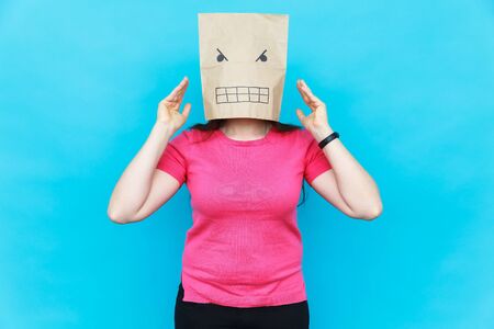 Woman standing with a cardboard on her head with angry face. Emotions concept.の写真素材
