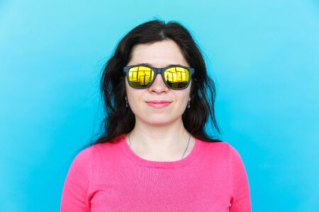 Fashion happy pretty smiling woman wearing a sunglasses over colorful blue background