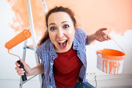 Renovation, redecoration and repair concept - Funny woman painting wall in new home.の写真素材