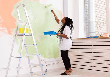 Afro american woman painting an apartment. Renovation, repair and redecoration conceptの写真素材