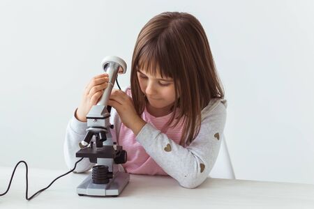 Schoolgirl using microscope in science class. Technologies, lessons and children concept.