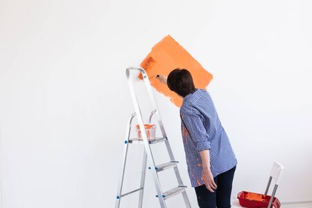 Lovely middle-aged woman painting wall. Renovation, redecoration and repair.の写真素材
