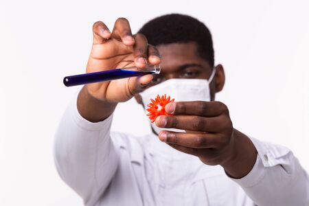 Medical doctor or laborant holding tube with Coronavirus vaccine for COVID-19. Coronavirus model in human hand. Vaccine development concept.の写真素材