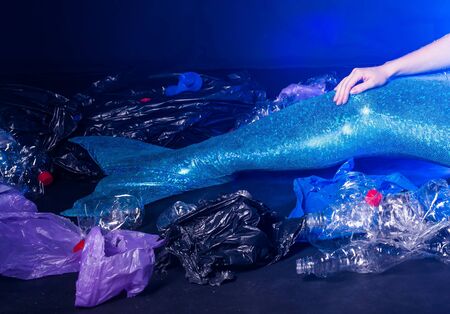 Ocean pollution, rubbish in the water. Sad fairytale mermaid in dirty ocean. Plastic trash and garbage in water. Environmental problem, plastic bag and bottles polluting planetの写真素材