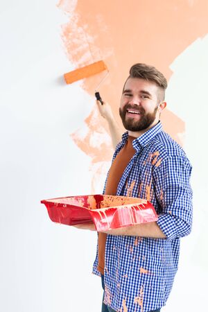 Happy man painting interior wall of home. Renovation, repair and redecoration concept.の写真素材