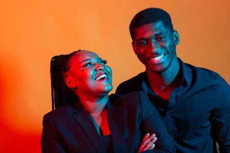 Dark neon portrait of young african american man and woman. Red and blue light.の写真素材