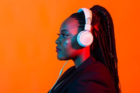 Neon portrait of young black woman listen to music in headphones.の写真素材