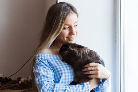 Pet and Easter concept - Happy girl hugging brown rabbit at home.の写真素材