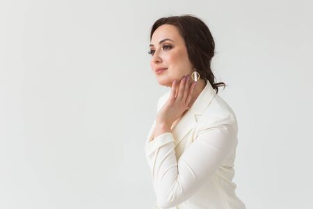 Girl in white suit with make-up posing on a white room. Fashion style body length studio portrait. Elegant fashionable woman. Copy space.の写真素材
