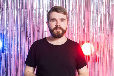 Party, carnival, holidays and emotional concept - Sad man against shiny background.
