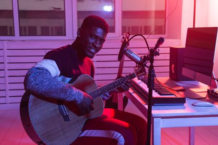 African american professional musician recording guitar in digital studio at home, music production technology concept.の写真素材