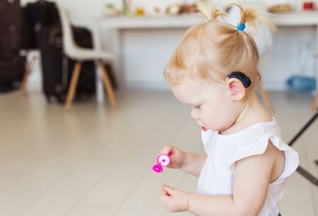 Baby girl wearing a hearing aid. Disabled child, disability and deafness.の写真素材