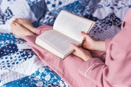 Close-up of woman wears pajama and relaxing at home and reading a book. Stay home. Quarantine pandemic coronavirus concept.の写真素材