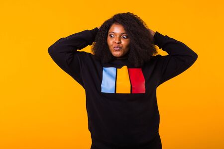 Youth fashion concept - Confident sexy black woman in stylish sweatshirt having fun on yellow...
