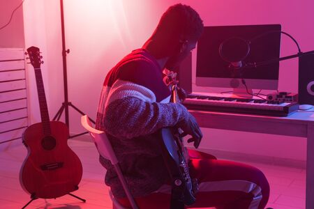 Create music and a recording studio concept - Bearded man guitarist recording electric guitar track...